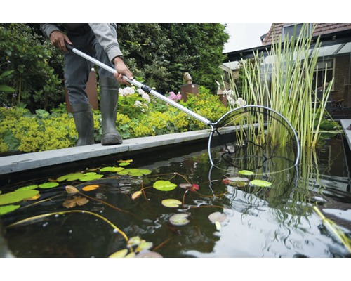 Vijveronderhoud met een schepnet om een tuinvijver schoon te maken