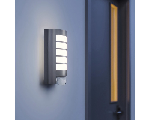 Brandende buitenwandlamp met bewegingssensor aan een muur