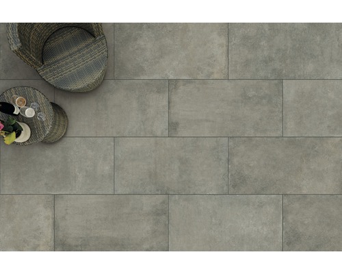 Bovenaanzicht met grijze terrastegels, rotan stoel en kleine tafel