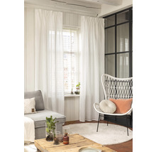 Woonkamer met bank, stoel, tafel, tapijt en witte gordijnen.