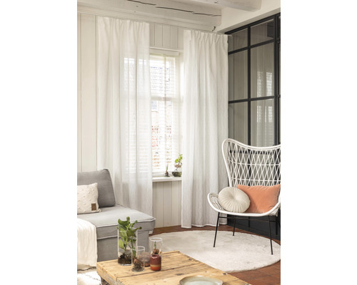 Woonkamer met bank, stoel, tafel, tapijt en witte gordijnen.