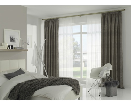 Lichte slaapkamer met bed, stoel en gordijnen aan een gordijnroede voor het raam.