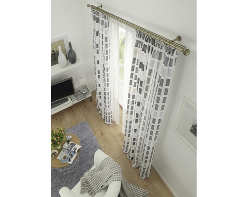 Woonkamer met gordijnen en overgordijnen met een geometrisch patroon aan een gordijnroede