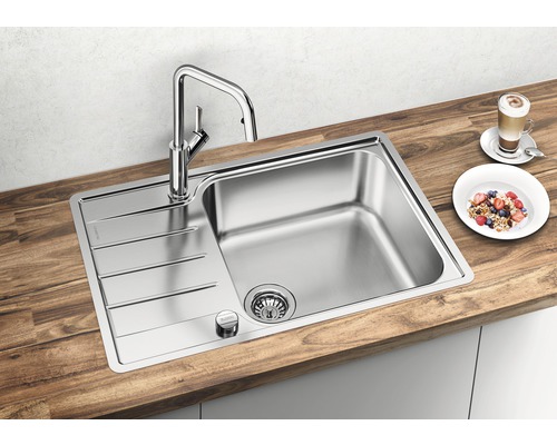 Roestvrijstalen spoelbak met afdruiprek en kraan op een houten werkblad