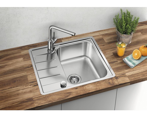 Roestvrijstalen spoelbak met afdruiprek en kraan op een houten werkblad