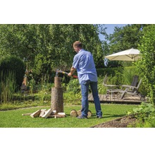 Man hakt hout met een bijl in de tuin.