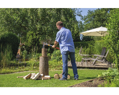 Man hakt hout met een bijl in de tuin.