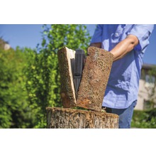 Een persoon hakt hout met een houtklover.