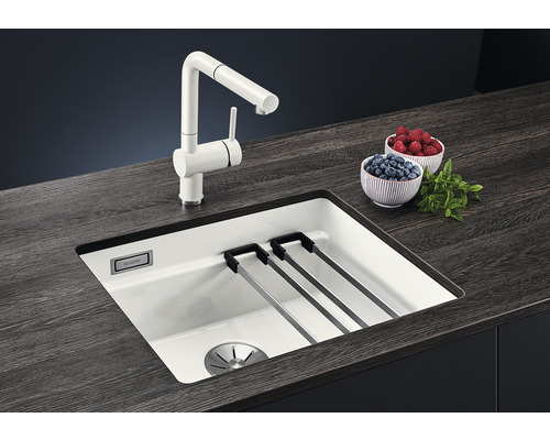 Keukenspoelbak met afdruiprek en kraan op een donker aanrechtblad met schalen met bessen