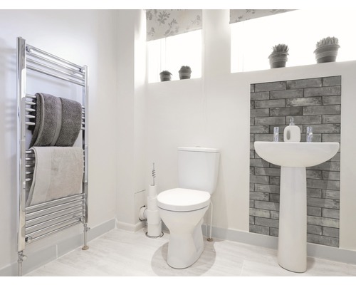 Lichte badkamer met toilet, wastafel, radiator en handdoeken.