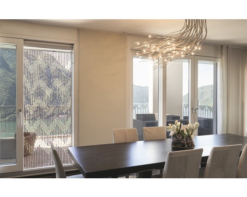 Eetkamer met eettafel, stoelen en bamboe rolgordijn voor het raam met uitzicht op het meer.