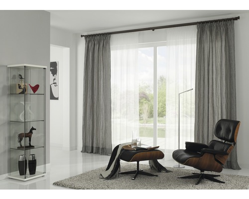 Woonkamer met gordijnen, fauteuil, vloerkleed en vitrine