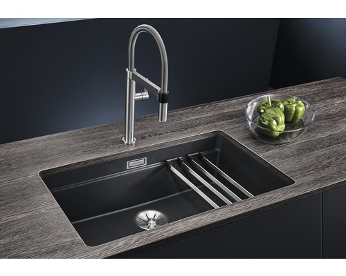 Spoelbak met afdruiprek, kraan en groene paprika''s in een kom