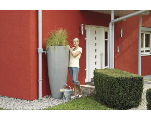 Scene met regenwatertank, beplanting en gieter voor een huis.