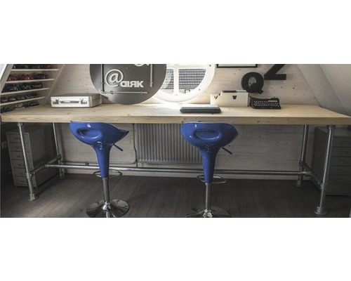 Lichte zolderkamer met houten bureau, buisframe en twee barkrukken.