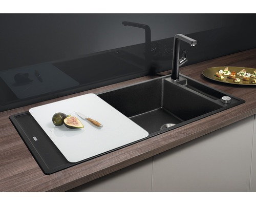 Zwarte gootsteen met kraan, snijplank, vijgen en mes.