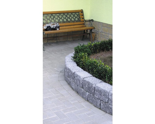 Tuinscene met stenen muur, pad van straatstenen en houten bank