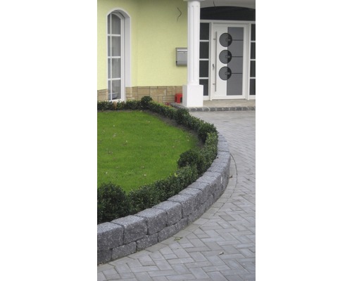 Tuinlandschap met gazon, stenen muur en verhard pad