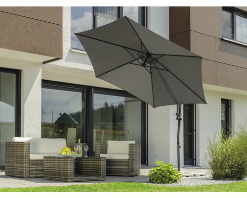 Scene met een rotan zithoek onder een rechthoekige parasol in de tuin