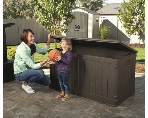 Foto van een vrouw en een kind voor een bruine opbergbox voor buiten in de tuin.