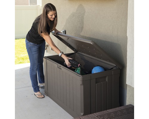 Vrouw opent een bruine tuinkist om tuingereedschap op te bergen