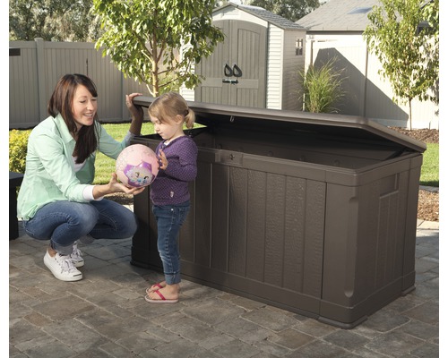 Bruine kunststof tuinkist met open deksel in de tuin met vrouw en kind