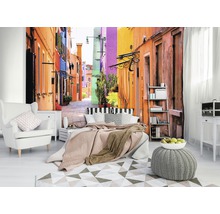 Woonkamer met fotobehang van een kleurrijk steegje, fauteuil, bed en tapijt