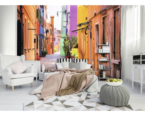 Woonkamer met fotobehang van een kleurrijk steegje, fauteuil, bed en tapijt
