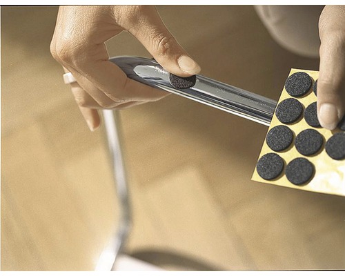 Persoon bevestigt een viltglijder aan een stoelpoot om de vloer te beschermen.