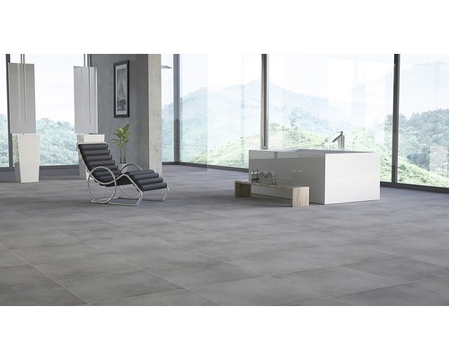 Lichte badkamer met grijze tegels, bad, ligstoel en grote ramen