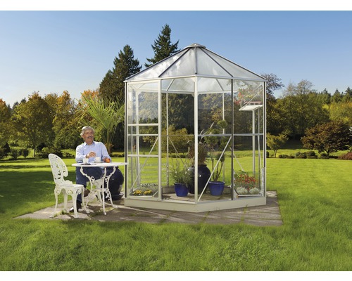 Vrijstaande glazen kas met man aan tafel