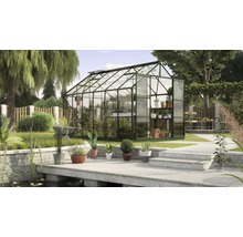 Kas met planten en tuingereedschap in een tuin.