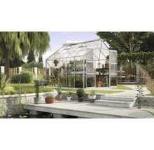 Broeikas met plantenrekken in een tuin met vijver