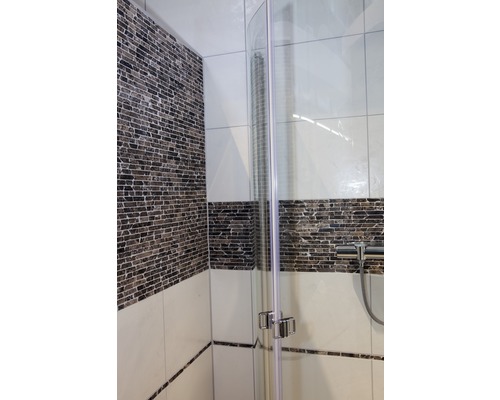 Detail van een douchecabine met glazen wand en tegels in de badkamer