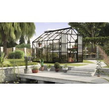 Glazen en metalen kas met planten in een tuin