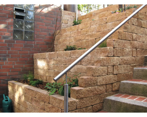 Gefaseerde tuinmuur van natuursteen met roestvrijstalen leuning en beplanting