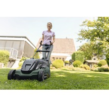 Vrouw bedient gazonmaaier in de tuin