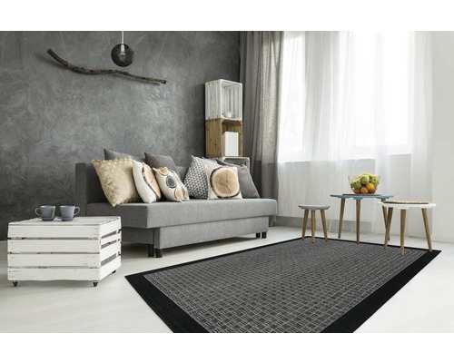 Woonkamer met grijze bank, kussens, houten tafel, grijs tapijt en decoratie