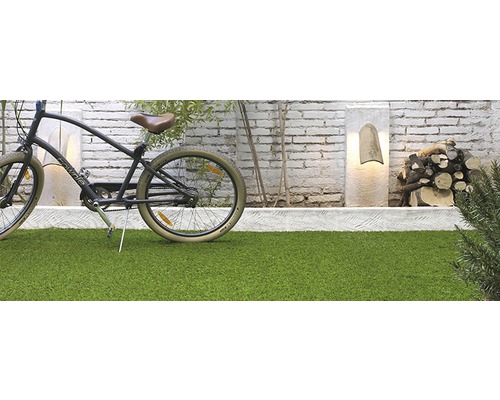 Scène met kunstgras, fiets, decoratieve stenen lampen en stapel hout