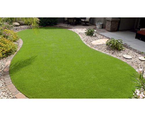 Kunstgrasveld in een tuin met stenen rand en decoratieve elementen.