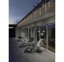 Buitenaanzicht van een huis met ijspegelverlichting, tuinmeubelen en terras.