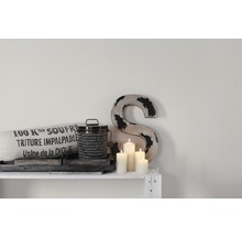 Decoratieve scène met kussen, blik, kaarsen en een S op een plank