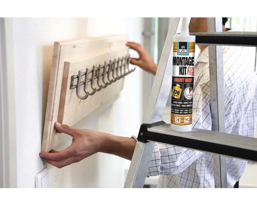 "Persoon monteert een houten kapstok met haken aan de muur