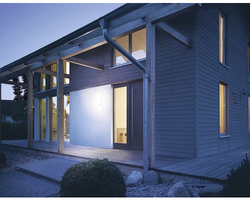 Verlicht woonhuis met houten gevel en houten terras in de schemering