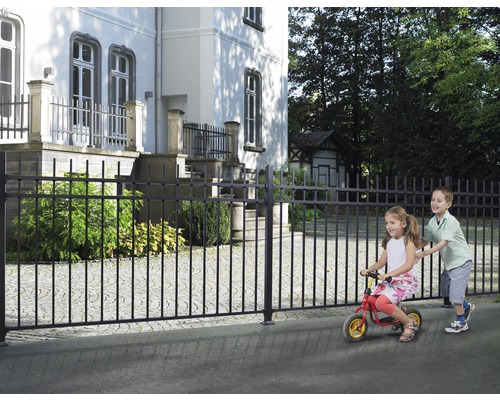 Zwart metalen hek voor een gebouw met spelende kinderen