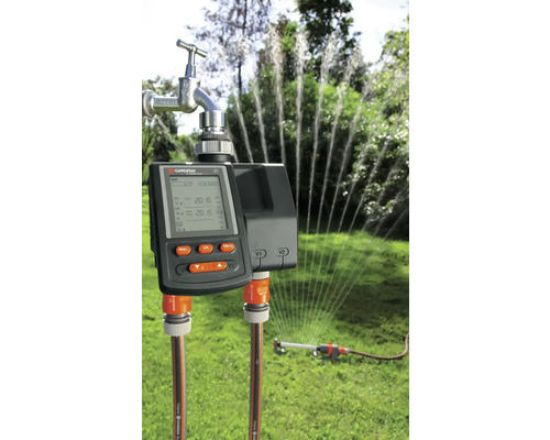 Gardena besproeiingscomputer met aangesloten tuinslang en gazonsproeier in werking