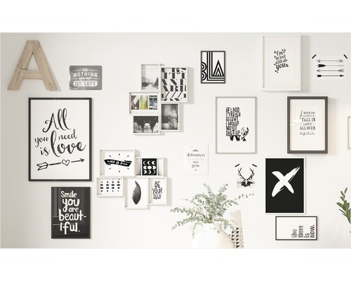 Wanddecoratie met verschillende foto''s, posters en een houten letter A op een witte muur.