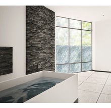 Badkamer met bad, raam en stenen muur