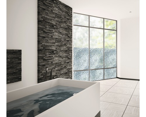 Badkamer met bad, raam en stenen muur