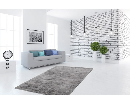 Lichte woonkamer met bank, vloerkleed en bakstenen muur